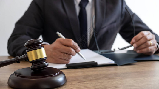 法律咨询和司法概念男律师或公证人处理重要案件的文件和报告以及木槌